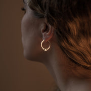 profile of a model wearing silver hoops with detail of an eye 