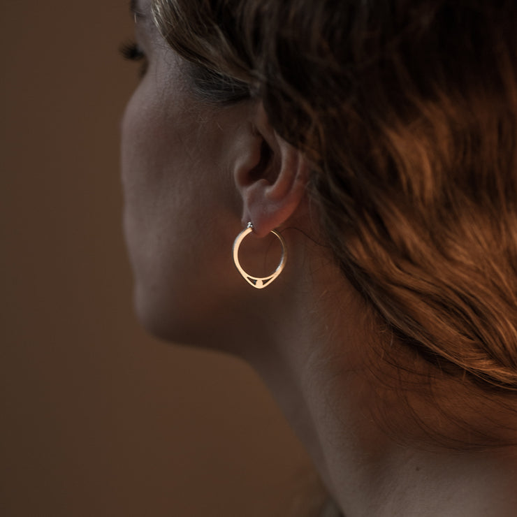 profile of a model wearing silver hoops with detail of an eye 