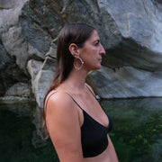 picture of the profile of a woman wearing a square shaped silver ear cuff and a silver hoop, in the background is a river and massive boulders 