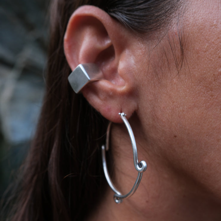 and ear decorated with a square shaped silver ear cuff and a silver hoop