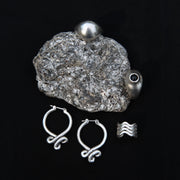product shoot of sphere rings, big piece of micah, nipple ring with black onyx cabochon, wavy ear cuff , and silver hoops 