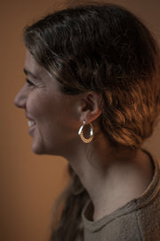 detail of a models ear wearing Silver hoops with graphic details reminiscent of lace