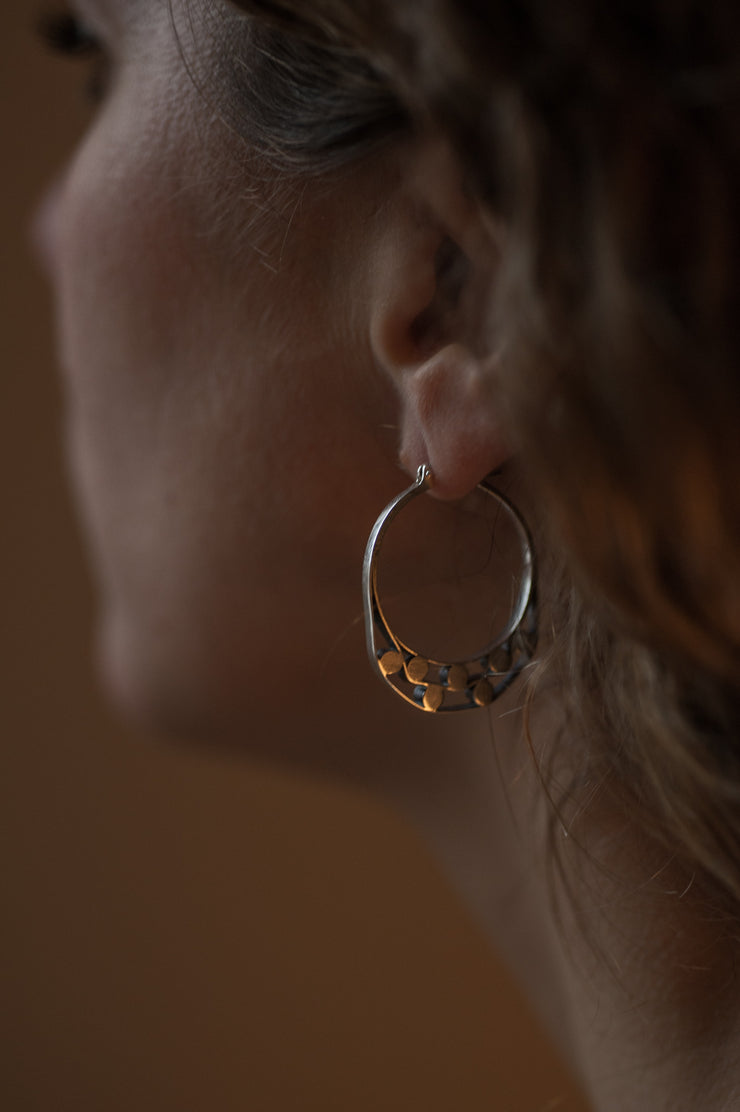 details of a models ear wearing Silver hoops with graphic details
