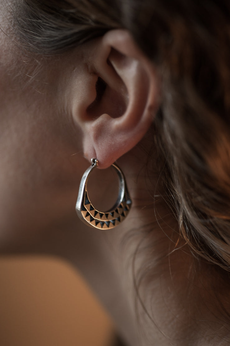 detail of a model wearing silver hoop with graphic details