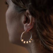 detail of a models ear wearing Silver hoops with graphic details reminiscent of lace