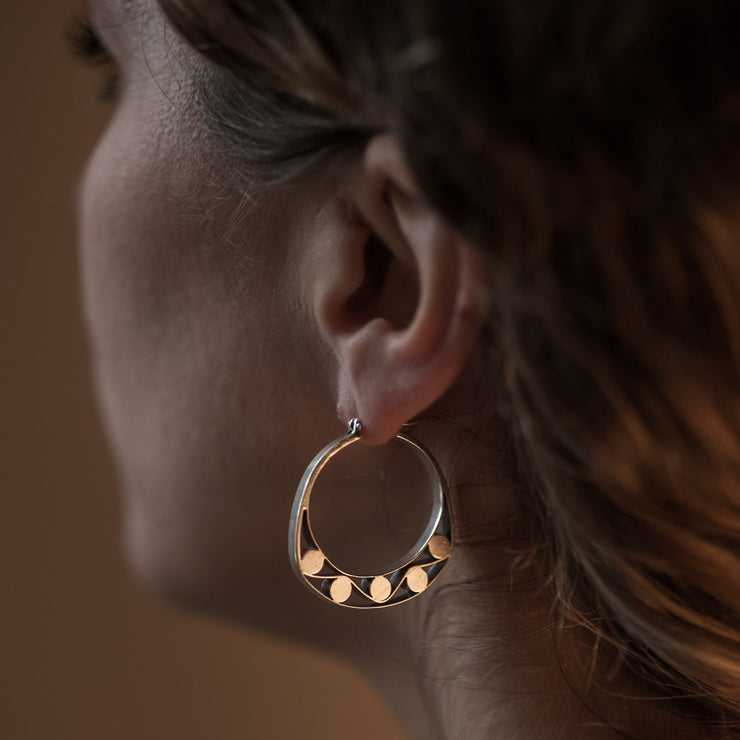 detail of a models ear wearing Silver hoops with graphic details reminiscent of lace