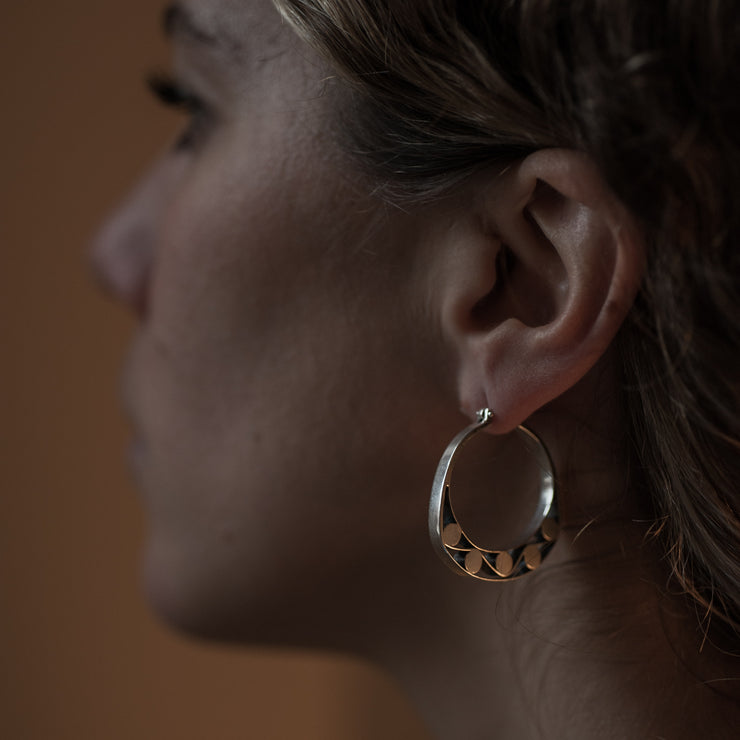 detail of a models ear wearing Silver hoops with graphic details reminiscent of lace