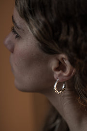 detail of a model wearing silver hoop with graphic details