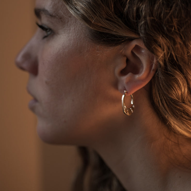 Detail of Gold hoops on a model. 14K Gold hoops with graphic details reminiscent of lace. These Earrings are made of Fairmined Gold, extracted from Fair trade mines in Colombia and Peru.