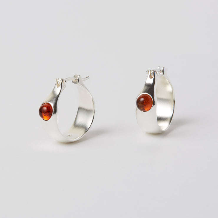 The Gem Hoops is an everyday hoop, with a hint of color added by the semiprecious gem. The earrings come in sterling silver or brass and have a hinged ear wire made of sterling silver. They measure about 3/4 of an inch diameter and are now available as singles so different gem stones can be paired together.   The semi precious gems sit in the front of the earrings come in Amber, Amethyst, Chalcedony, Citrine and Green Onyx and Peridot. Available at Suna Bonometti dot come